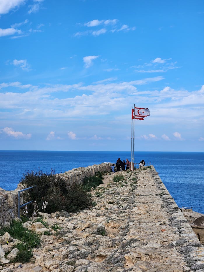 services-03 Historic Kyrenia Castle with flags overlooking the sea on a bright day.
